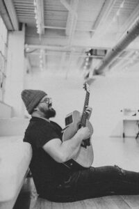 picture of dave hinrich with guitar sitting by couch
