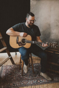 picture of dave hinrich smiling and looking down at guitar